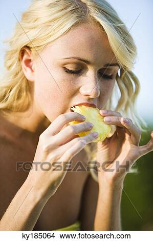 Portrait of a young blond woman eating pineapple slice View Large Photo Image Picture - Portrait of a young blond woman eating pineapple slice. Fotosearch