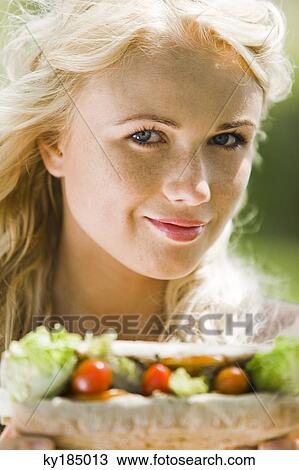 Portrait of a young blond woman holding a sandwich View Large Photo Image Stock Image - Portrait of a young blond woman holding a sandwich. Fotosearch