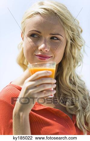 Portrait of a young blond woman holding a fruit juice glass View Large Photo Image Stock Image - Portrait of a young blond woman holding a fruit juice glass. Fotosearch
