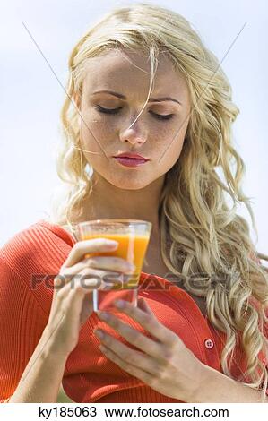 Portrait of a young blond woman holding a fruit juice glass View Large Photo Image Stock Image - Portrait of a young blond woman holding a fruit juice glass. Fotosearch