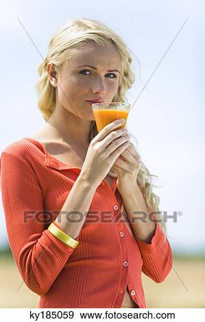 Portrait of a young blond woman holding a fruit juice glass View Large Photo Image Stock Photo - Portrait of a young blond woman holding a fruit juice glass. Fotosearch