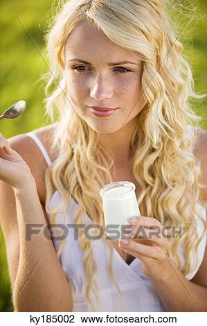 Portrait of young woman eating a yoghurt View Large Photo Image Stock Image - Portrait of young woman eating a yoghurt. Fotosearch