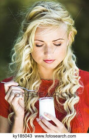 Portrait of young woman eating a yoghurt View Large Photo Image Stock Image - Portrait of young woman eating a yoghurt. Fotosearch