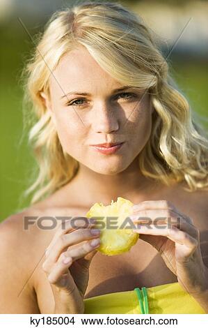 Young woman eating a slice of pineapple View Large Photo Image Picture - Young woman eating a slice of pineapple. Fotosearch