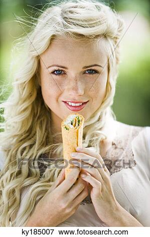 Stock Photo - Young woman eating enchilada. Fotosearch