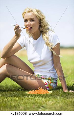 Young woman eating grated carrots View Large Photo Image Stock Photo - Young woman eating grated carrots. Fotosearch