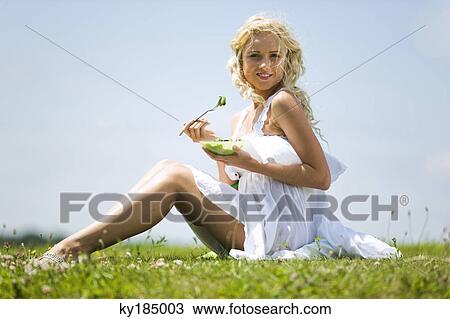 Stock Image - Young woman eating vegetables. Fotosearch