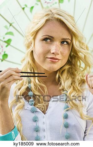Young woman holding chopsticks and umbrella View Large Photo Image Stock Photo - Young woman holding chopsticks and umbrella. Fotosearch