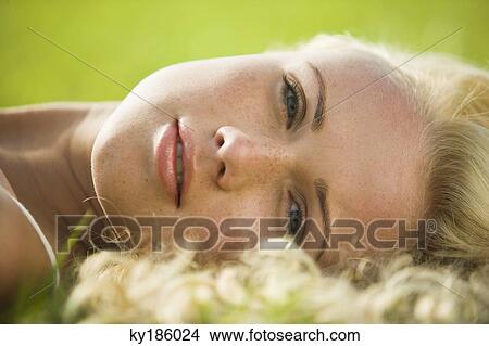 Portrait of a young woman lying in grass View Large Photo Image Picture - Portrait of a young woman lying in grass. Fotosearch