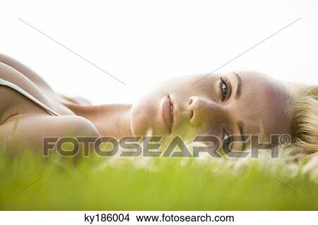 Young woman lying in the grass View Large Photo Image Picture - Young woman lying in the grass. Fotosearch