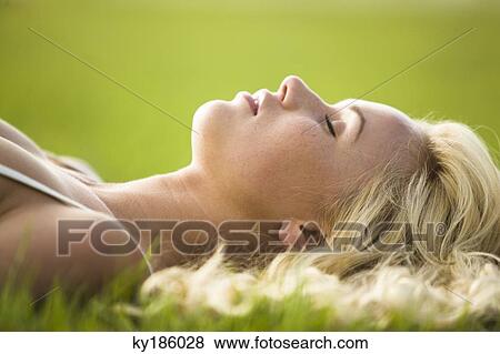 Stock Photo - Young woman lying in the grass. Fotosearch