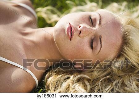 Young woman lying on the grass View Large Photo Image Stock Image - Young woman lying on the grass. Fotosearch