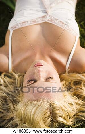 Young woman lying on the grass View Large Photo Image Stock Photography - Young woman lying on the grass. Fotosearch