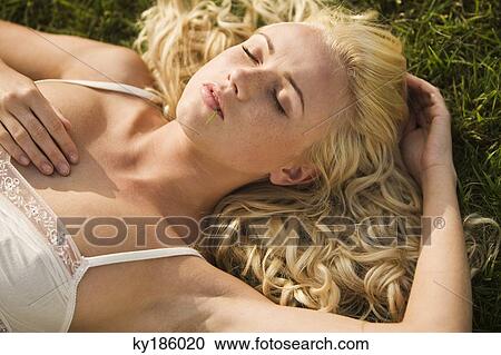 Stock Image - Young woman sleeping in grass. Fotosearch