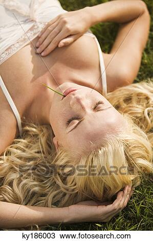 Young woman sleeping lying in the grass View Large Photo Image Stock Image - Young woman sleeping lying in the grass. Fotosearch