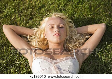 Stock Image - Young woman sleeping on the grass. Fotosearch