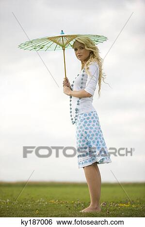 Young woman holding an umbrella View Large Photo Image Stock Photograph - Young woman holding an umbrella. Fotosearch