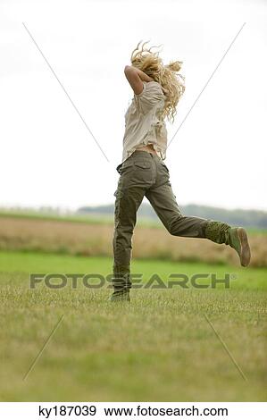 Young woman running on the grass View Large Photo Image Stock Photo - Young woman running on the grass. Fotosearch