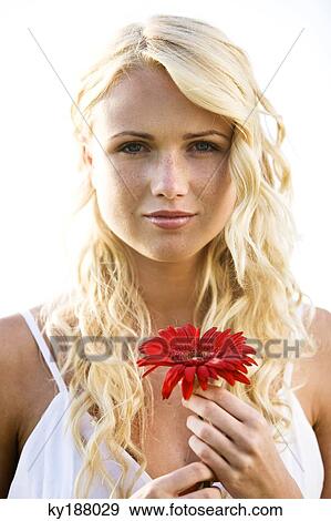 Stock Photo - Portrait of a young woman holding a red flower. Fotosearch