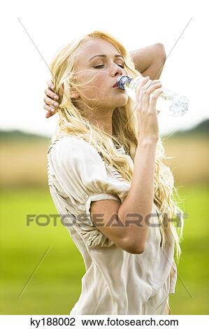 Stock Image - Young woman drinking water from a bottle. Fotosearch
