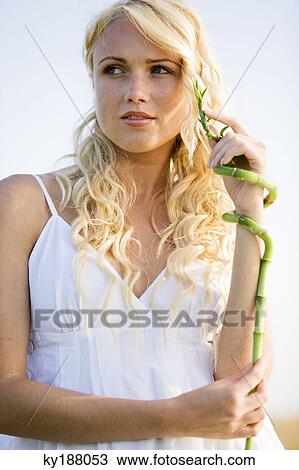 Stock Image - Young woman holding bamboo. Fotosearch