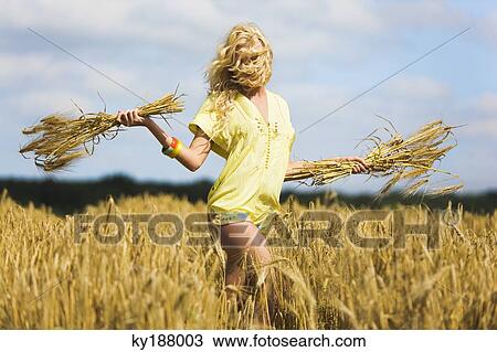 Young woman holding wheat in a field View Large Photo Image Stock Image - Young woman holding wheat in a field. Fotosearch