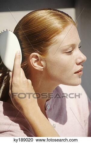 Young woman brushing her hair, outdoors View Large Photo Image Stock Image - Young woman brushing her hair, outdoors. Fotosearch