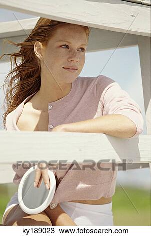 Stock Image - Young woman sitting on a balcony. Fotosearch