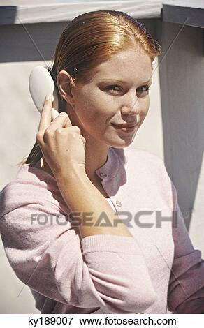 Stock Photo - Young woman sitting on a balcony, brushing her hair. Fotosearch