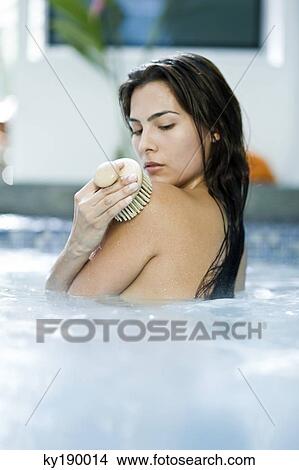 Rear view of a woman rubbing her skin with a back brush View Large Photo Image Picture - Rear view of a woman rubbing her skin with a back brush. Fotosearch