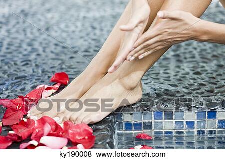 Woman massaging her legs at the poolside View Large Photo Image Stock Photo - Woman massaging her legs at the poolside. Fotosearch