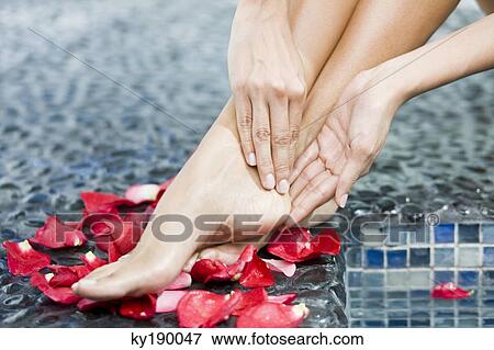 Woman massaging her legs at the poolside View Large Photo Image Stock Photo - Woman massaging her legs at the poolside. Fotosearch