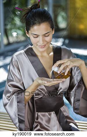 Woman pouring oil on her hand from a dispenser View Large Photo Image Stock Photo - Woman pouring oil on her hand from a dispenser. Fotosearch
