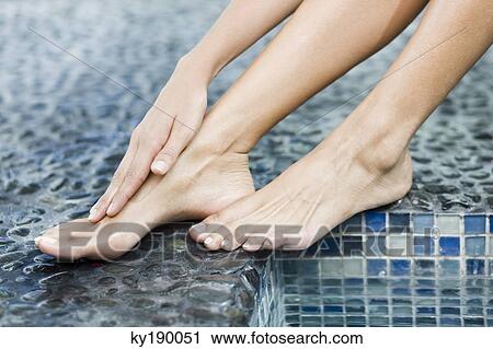Woman rubbing her foot at the poolside View Large Photo Image Stock Image - Woman rubbing her foot at the poolside. Fotosearch