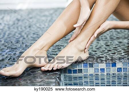 Woman rubbing her legs at the poolside View Large Photo Image Stock Photography - Woman rubbing her legs at the poolside. Fotosearch