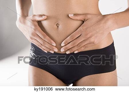 Mid section view of a woman touching her abdomen View Large Photo Image Stock Photograph - Mid section view of a woman touching her abdomen. Fotosearch