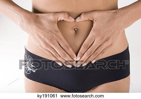 Woman making a heart shape with hands around belly button View Large Photo Image Stock Image - Woman making a heart shape with hands around belly button. Fotosearch