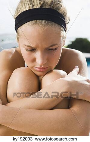 Close-up of a woman hugging her knees and looking serious View Large Photo Image Stock Image - Close-up of a woman hugging her knees and looking serious. Fotosearch