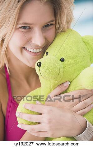 Stock Photo - Portrait of a woman holding a teddy bear and smiling. Fotosearch