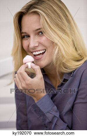 Stock Image - Woman eating a mushroom shaped candy. Fotosearch