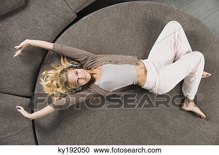 Woman lying on a round sofa and listening to music View Large Photo Image Stock Image - Woman lying on a round sofa and listening to music. Fotosearch