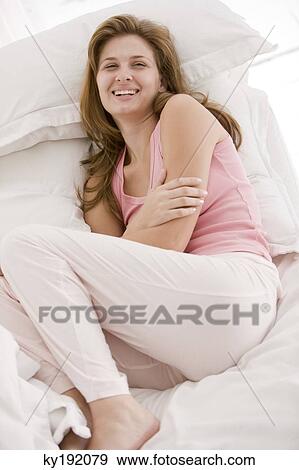 Woman resting on the bed and smiling View Large Photo Image Stock Photo - Woman resting on the bed and smiling. Fotosearch