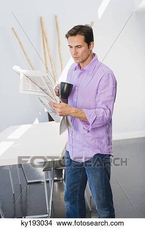 Man reading a newspaper and drinking a cup of coffee View Large Photo Image Picture - Man reading a newspaper and drinking a cup of coffee. Fotosearch