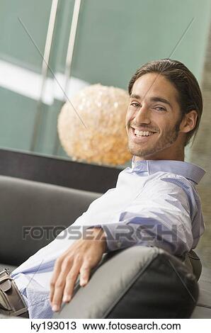Man sitting on a couch View Large Photo Image Stock Image - Man sitting on a couch. Fotosearch