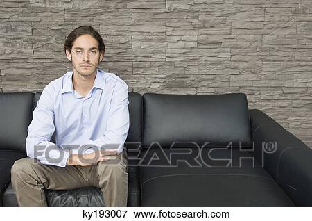 Man sitting on a couch View Large Photo Image Stock Photo - Man sitting on a couch. Fotosearch