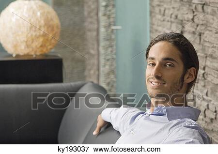 Man sitting on a couch View Large Photo Image Stock Photo - Man sitting on a couch. Fotosearch