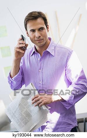 Man talking on a mobile phone and holding a newspaper View Large Photo Image Picture - Man talking on a mobile phone and holding a newspaper. Fotosearch