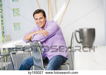 Portrait of a man sitting on a chair and smiling View Large Photo Image Stock Photo - Portrait of a man sitting on a chair and smiling. Fotosearch