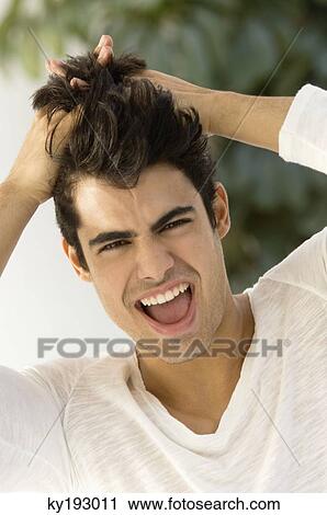 Stock Image - Portrait of a man with his hands in his hair. Fotosearch