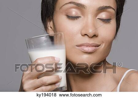 Close-up of a woman holding a glass of milk View Large Photo Image Stock Photo - Close-up of a woman holding a glass of milk. Fotosearch